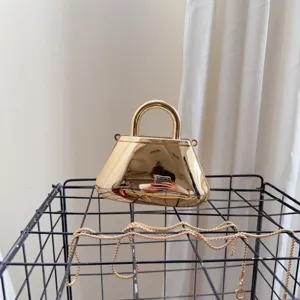 Dettaglio di una borsa da sera in acrilico dorato riflettente con manico in metallo
