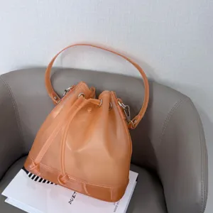 Detailed view of a matte orange TPU jelly bucket bag with drawstring closure on a magazine.