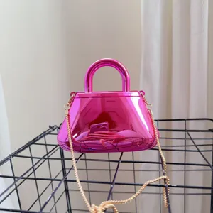 Dettaglio di una borsa da sera in acrilico rosa metallizzato con una catena dorata lucida