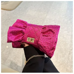 Pochette de soirée élégante en forme de nœud fuchsia avec strass et chaîne.
