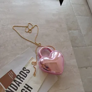 Detail view of a stylish heart-shaped acrylic evening bag in metallic pink finish