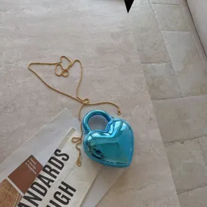 Detailed view of metallic blue heart-shaped acrylic handbag with elegant gold chain