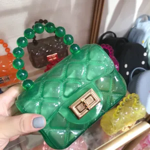 Close-up of green jelly mini bag with quilted pattern and beaded handle
