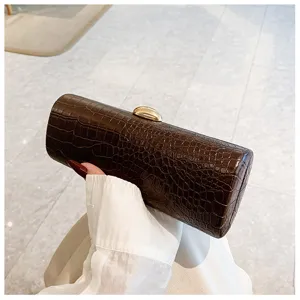 Detail view of a hand holding a retro brown crocodile pattern baguette clutch bag