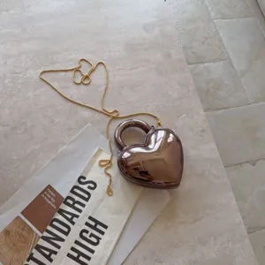 Close-up detail of heart-shaped acrylic evening clutch bag with elegant gold chain strap
