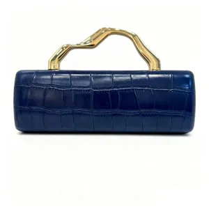 Detail of dark blue crocodile texture clutch with wavy gold metal handle