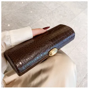 Detailed macro shot of a brown crocodile pattern baguette clutch with a gold clasp