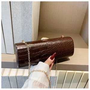 Detailed view of brown crocodile pattern baguette clutch bag with gold chain