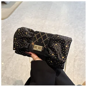 Gros plan d'une pochette noeud en velours noir avec strass dorés et fermoir