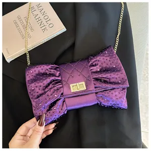 Détail d'une pochette nœud violette élégante ornée de strass et d'une chaîne dorée.