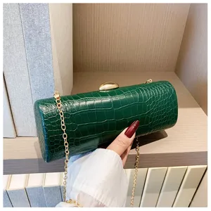 Macro view of a green crocodile texture cylinder clutch bag with an elegant gold chain