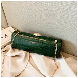 Close-up of green crocodile texture on a vintage baguette-style clutch bag with chain.
