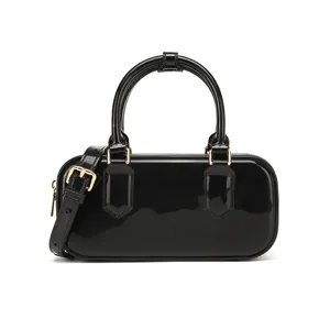 Primo piano di una borsa in vernice nera lucida con eleganti finiture in metallo dorato.