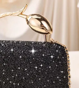 Detail view of shimmering black rhinestone evening clutch featuring a gold tulip handle.
