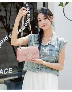 Young woman holding a pink quilted chain bag with a gold interlocking buckle.
