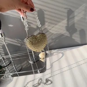 Macro detail of a heart-shaped evening bag with gold rhinestones and beaded handle