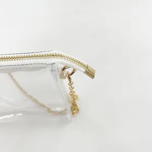 Macro detail of the gold zipper and chain attachment on a clear jelly crossbody bag