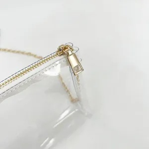 Macro detail showing the high-quality gold metal zipper and teeth of a clear PVC jelly bag.