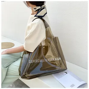 Detailed view of a large transparent brown PVC jelly tote bag with white letter print.