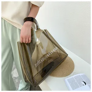 Detailed view of the large smoke-gray transparent PVC jelly tote bag held by a model.