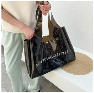 Close-up detail of a large black semi-transparent PVC jelly tote bag with white text