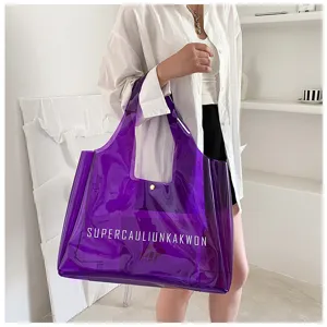 Fashionable purple transparent PVC jelly tote bag with bold white letter print held by a model.
