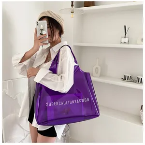 Fashionable large purple transparent PVC jelly tote bag with lettering held by a model.