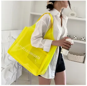 Model wearing a large yellow transparent PVC jelly tote bag in a casual indoor setting.