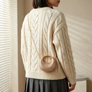 Luxury gold rhinestone evening bag with chain strap worn on cream cable knit sweater