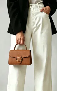 Close-up of a brown leather wallet handbag with a stylish gold oval clasp detail