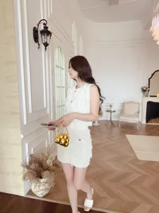Femme élégante tenant un mini sac de soirée doré en forme de cœur dans une pièce.