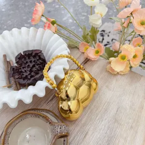Gros plan d'une pochette bulle dorée avec poignée perlée et fleurs décor