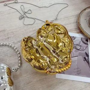 Vue détaillée d'une mini pochette de soirée dorée en forme de cœur avec chaîne.