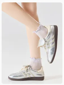 Detail shot of breathable mesh ruffle lace socks paired with silver casual fashion sneakers.