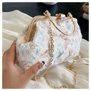 Nahaufnahme einer eleganten Abendtasche mit Schmetterlingsstickerei und Goldkette