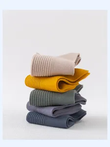 Gros plan détaillé de chaussettes unies empilées avec texture fine et belles couleurs douces.