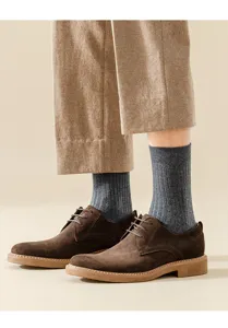 Close-up detail of men's ribbed wool mid-calf socks styled with classic brown suede shoes.