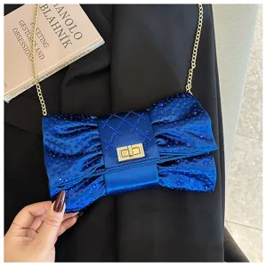 Pochette de soirée élégante en forme de nœud bleu avec strass et chaîne dorée.
