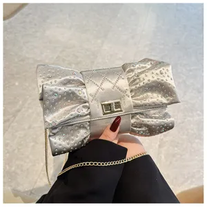 Détail du sac de soirée argenté en forme de nœud avec des strass étincelants.