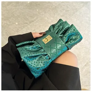 Gros plan de la pochette de soirée vert émeraude avec strass et serrure dorée.