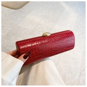 Close-up detail of a vintage red crocodile textured baguette clutch bag with gold clasp