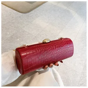 Red crocodile-embossed long baguette clutch bag with elegant gold chain strap held by hand