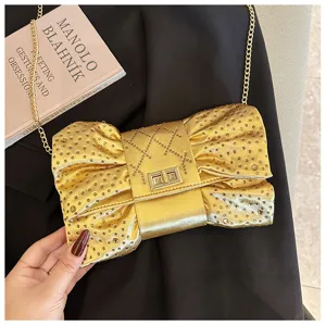 Détail d'une pochette dorée luxueuse en forme de nœud avec des strass étincelants.