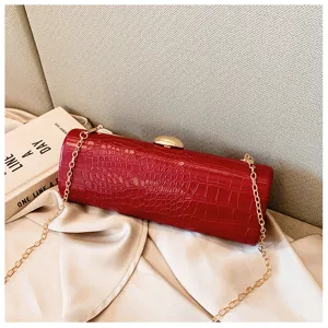 Detail of red crocodile embossed baguette bag with golden chain strap for evening party