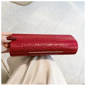 Close-up detail of a red crocodile-embossed long baguette clutch bag with gold chain.