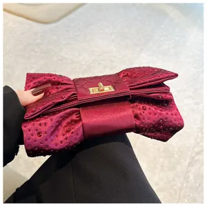 Détail d'une élégante pochette nœud bordeaux étincelante ornée de strass brillants.