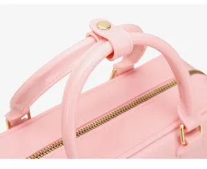 Primer plano de las asas y la cremallera dorada del bolso Boston de gelatina rosa.