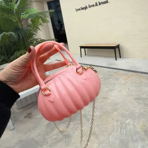 Gros plan sur un sac à main créatif en PVC rose en forme de citrouille et chaîne