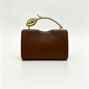 Elegant detail of the golden rose stem handle on a premium brown leather clutch bag