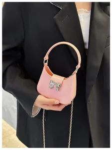 Macro view of a pink PVC jelly bag featuring a silver bow buckle and gold chain.